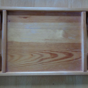 May include: A wooden serving tray with two handles on the sides. The tray is made of light brown wood with a natural finish.