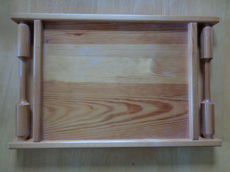 May include: A wooden serving tray with two handles on the sides. The tray is made of light brown wood with a natural finish.