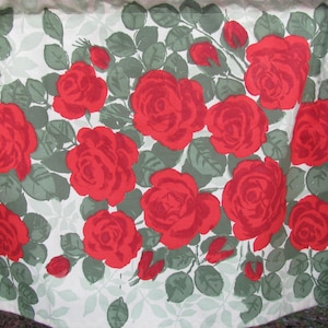 May include: A white fabric with a repeating pattern of red roses and green leaves.