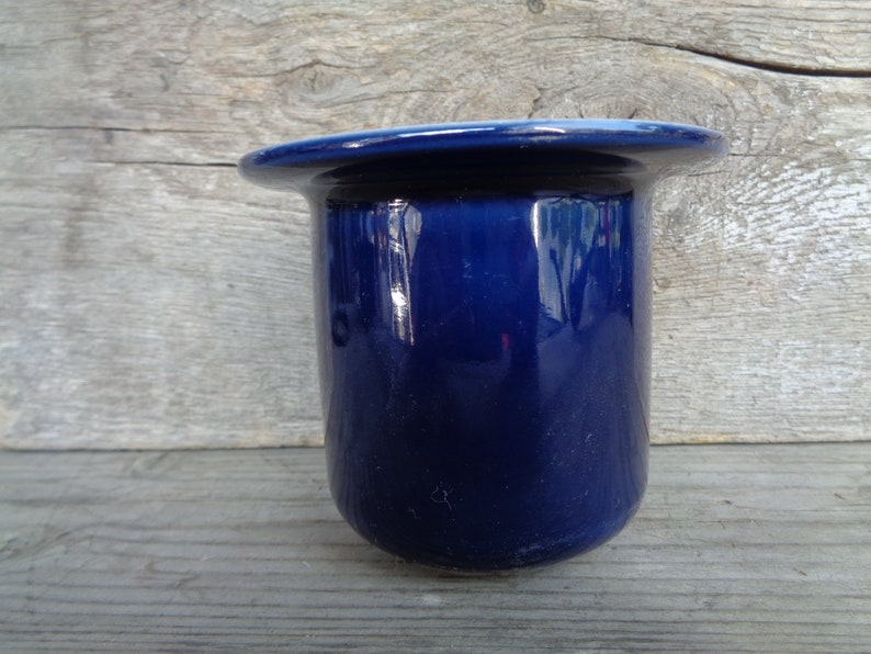 May include: A dark blue ceramic toothbrush holder with a smooth, glossy finish.