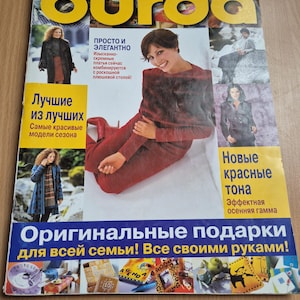 May include: A magazine cover with the word "burda" in large yellow letters. The cover features images of fashion models and text in Russian, including "Original gifts for the whole family!" and "New red tones."