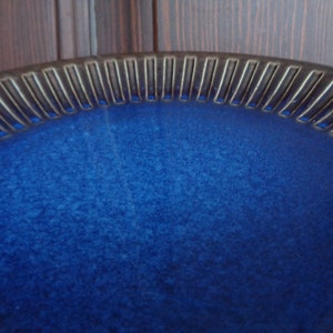 May include: A deep blue ceramic bowl with a textured rim. The bowl has a slightly speckled glaze.