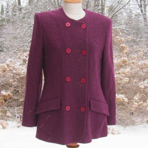 May include: A burgundy double-breasted jacket with red buttons. The jacket has a fitted silhouette and a textured fabric.