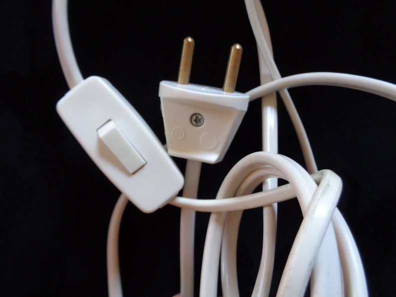 K&ouml;nnte beinhalten: Ein wei&szlig;es Stromkabel mit einem wei&szlig;en Inline-Schalter und einem wei&szlig;en Stecker mit zwei Stiften.