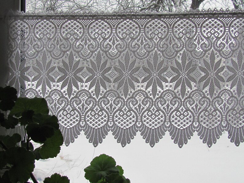 May include: White lace curtain with a delicate floral pattern. The lace is a traditional design with a scalloped edge.
