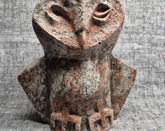 Könnte beinhalten: Handgeschnitzte Eulen-Skulptur mit strukturierter, rotbrauner Oberfläche und grüner Patina. Die Eule hat ein stilisiertes Design mit großen Augen und einem markanten Schnabel, das eine einzigartige, künstlerische Ästhetik zeigt.