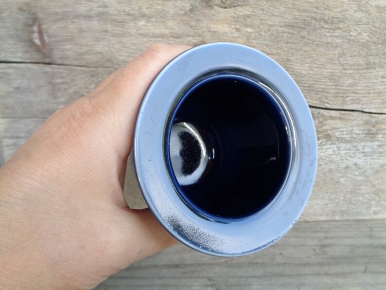 May include: A blue ceramic cup with a white rim. The cup is empty and the inside is visible.