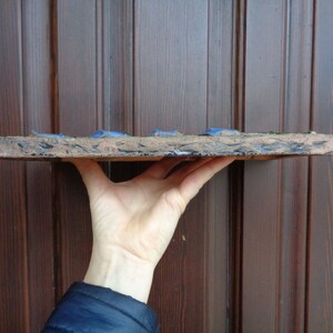 K&ouml;nnte beinhalten: Eine rechteckige Keramikfliese mit einer rauen, strukturierten Oberfl&auml;che. Die Fliese ist mit einer blauen und gr&uuml;nen Glasur verziert, die einen marmorierten Effekt erzeugt. Die Fliese wird von einer Hand gehalten, wodurch ihre Gr&ouml;&szlig;e und Form hervorgehoben werden.