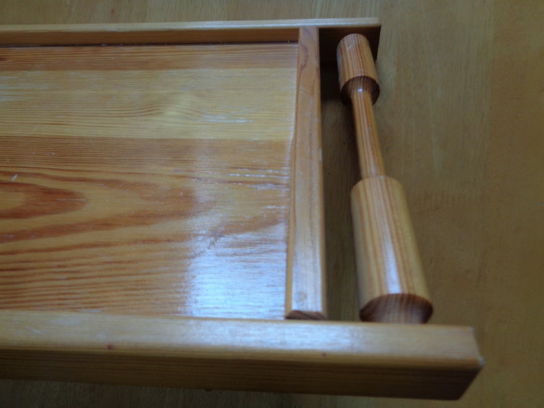 May include: A wooden serving tray with a natural finish and a wooden handle. The tray has a rectangular shape and is made of light-colored wood.