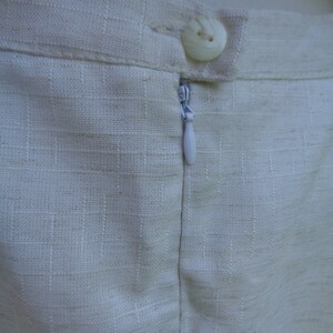May include: A white linen skirt with a zipper closure and a single button at the top.