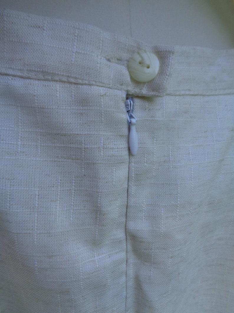 May include: A white linen skirt with a zipper closure and a single button at the top.