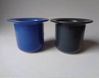 May include: Two ceramic planters, one blue and one dark gray, with a wide rim.
