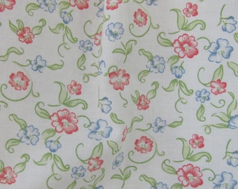 May include: White fabric with a repeating pattern of small pink and blue flowers with green stems. The fabric has a subtle texture.