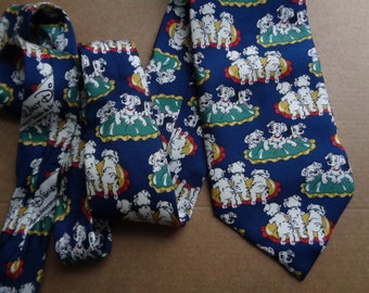 May include: A blue silk tie with a repeating pattern of Dalmatian puppies on a yellow and green background. The tie has a Disney label with the text "Walt Disney World" and "The Home of the Magic."