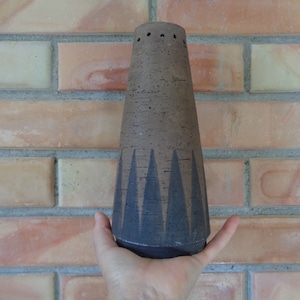 May include: A brown ceramic vase with a geometric black design. The vase has a narrow opening and a wide base.