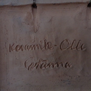 K&ouml;nnte beinhalten: Nahaufnahme einer Terrakotta-Fliese mit der Aufschrift "Keramik-Ollie" und der Unterschrift "Grandma".