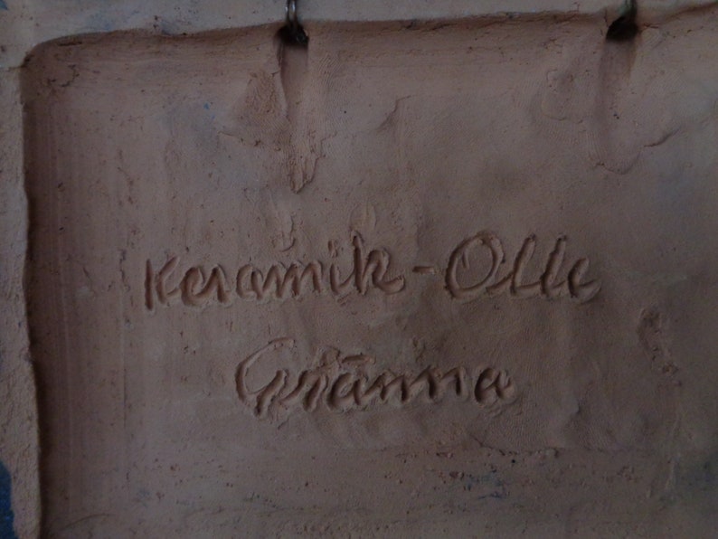 K&ouml;nnte beinhalten: Nahaufnahme einer Terrakotta-Fliese mit der Aufschrift "Keramik-Ollie" und der Unterschrift "Grandma".