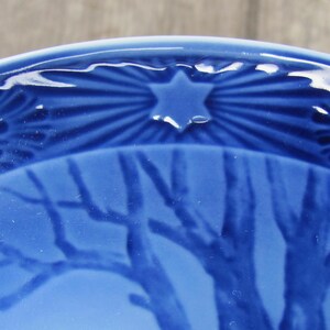 May include: A blue ceramic plate with a star and a tree design. The star is in the center of the plate and the tree is on the bottom half of the plate.