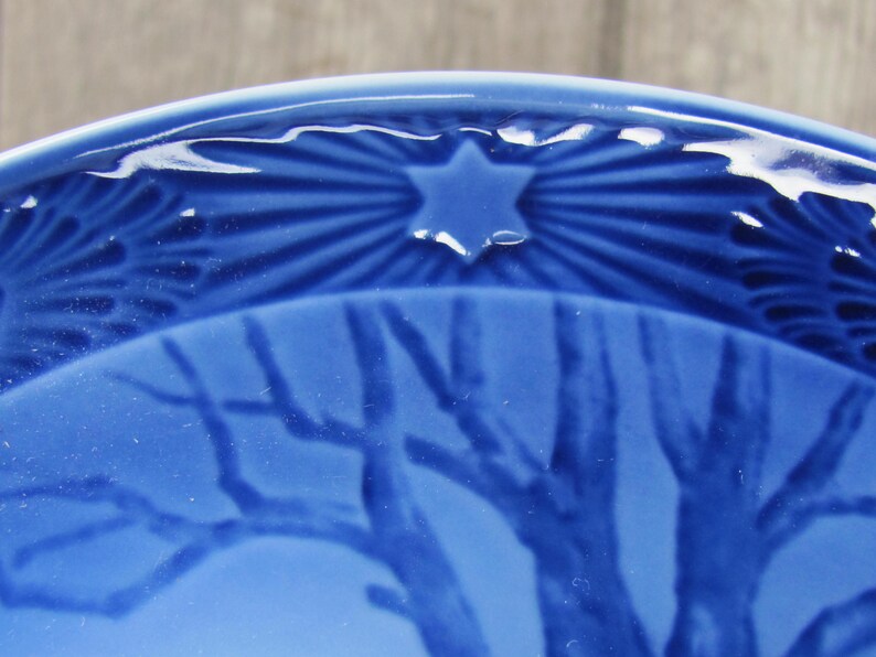 May include: A blue ceramic plate with a star and a tree design. The star is in the center of the plate and the tree is on the bottom half of the plate.