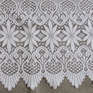 May include: White lace fabric with a delicate floral pattern. The lace has a scalloped edge and is perfect for crafting projects.