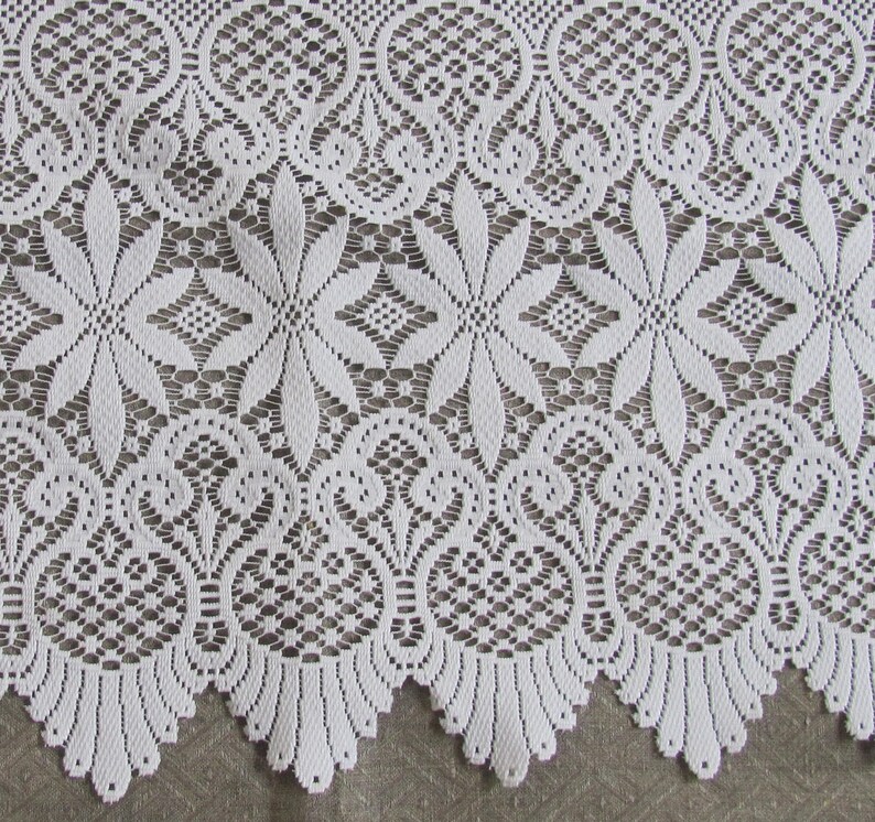 May include: White lace fabric with a delicate floral pattern. The lace has a scalloped edge and is perfect for crafting projects.