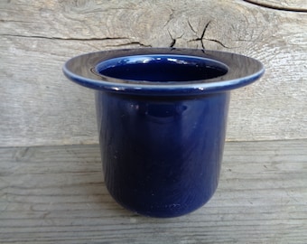 May include: A dark blue ceramic toothbrush holder with a wide rim.