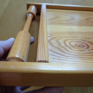May include: A wooden serving tray with a natural finish and a wooden handle. The tray has a rectangular shape and is made of light-colored wood.