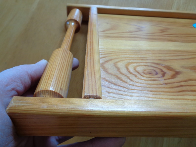 May include: A wooden serving tray with a natural finish and a wooden handle. The tray has a rectangular shape and is made of light-colored wood.