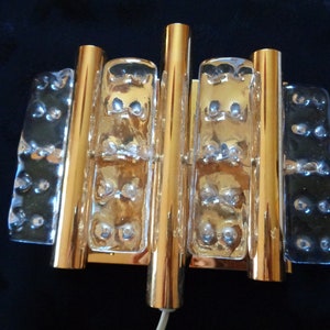 K&ouml;nnte beinhalten: Goldene Wandleuchte mit klaren Glasplatten. Die Glasplatten haben eine strukturierte Oberfl&auml;che mit kleinen Blasen.