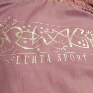 May include: A pink jacket with a silver logo that says "Snowing" and "LUHTA SPORT" in a stylised font.