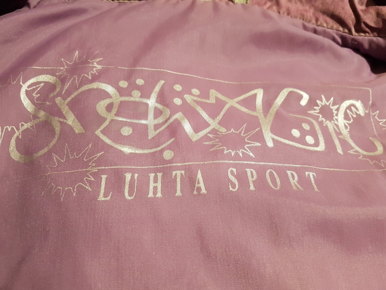 May include: A pink jacket with a silver logo that says "Snowing" and "LUHTA SPORT" in a stylised font.
