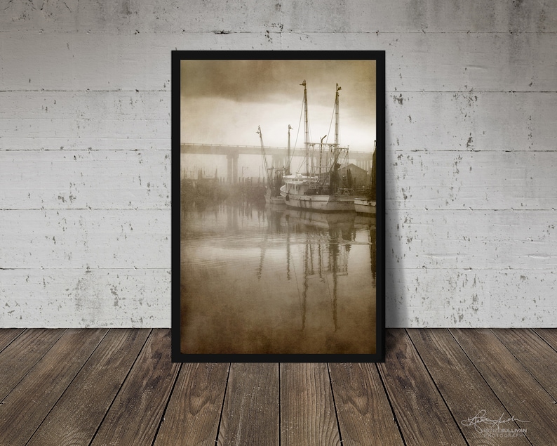 May include: A sepia-toned photograph of a fishing boat docked at a pier. The boat is surrounded by fog and the water is calm. The image is framed in a black frame.