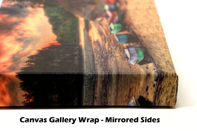 Puede incluir: Primer plano de un lienzo de galer&iacute;a envuelto con lados espejados. La imagen muestra una puesta de sol sobre un bosque con una fila de barcos coloridos en un muelle de madera.