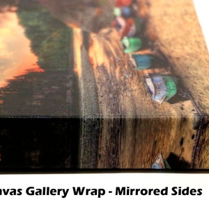 May include: A close-up of a canvas gallery wrap with mirrored sides. The image shows a sunset over a forest with a row of colorful boats on a wooden dock.