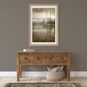 May include: A framed sepia-toned photograph of a fishing boat docked at a pier with a bridge in the background. The boat is surrounded by fog and the water is calm and reflective. The image is signed by the photographer, "Sally Sullivan Photography."