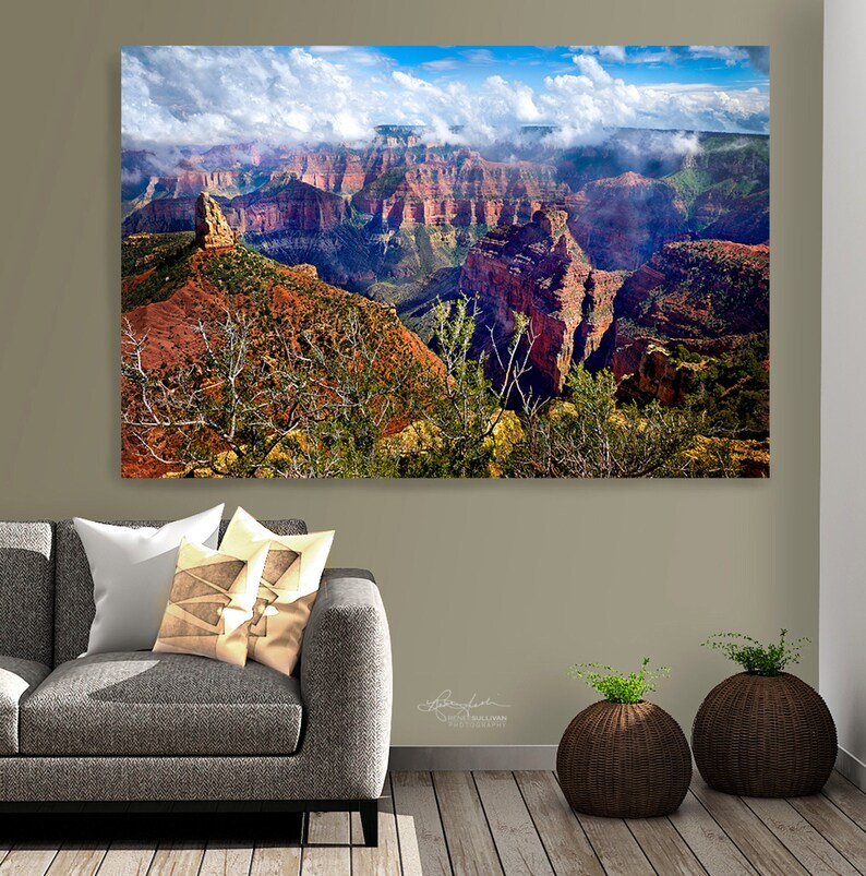 May include: A panoramic view of the Grand Canyon with red rock formations and a cloudy sky. The canyon is filled with fog and mist, creating a dramatic and ethereal scene.