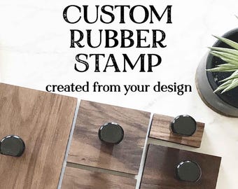 Puede incluir: Sellos de goma personalizados creados a partir de tu diseño. La imagen muestra varios bloques de madera con sellos de goma negros montados en ellos.
