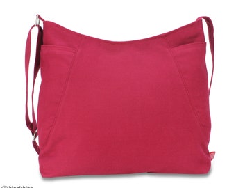 Könnte beinhalten: Eine weinrote Canvas-Tragetasche mit einem einzigen Trageriemen und zwei Taschen auf der Vorderseite. Die Tasche ist aus strapazierfähigem Canvas-Material gefertigt und hat ein schlichtes, klassisches Design.