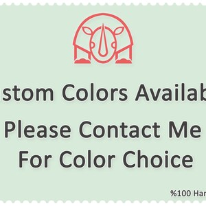May include: A light green square with a red rhino illustration. The text "Custom Colors Available" is written in black. Below the text is "Please Contact Me For Color Choice" in black. The bottom right corner of the square has the text "100% Handmade" in black.