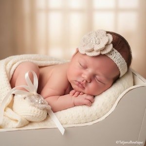 Puede incluir: Un bebé recién nacido durmiendo con una diadema de flores de ganchillo color crema con detalles de perlas. El bebé está acurrucado en una manta blanca y un par de botines a juego con una cinta de raso. El fondo es de color neutro.