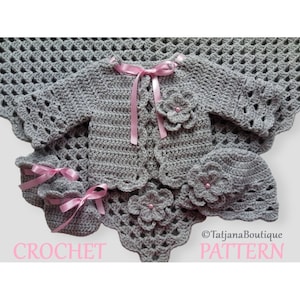 Könnte beinhalten: Ein Häkel-Babyset in Grau mit rosa Akzenten. Das Set beinhaltet eine Strickjacke, eine Mütze und Booties. Die Strickjacke hat eine Blumenstickerei auf der Vorderseite. Die Mütze und die Booties haben ebenfalls Blumenstickereien. Das Set ist mit einer zarten Häkelmasche gearbeitet.  ©TatjanaBoutique PATTERN