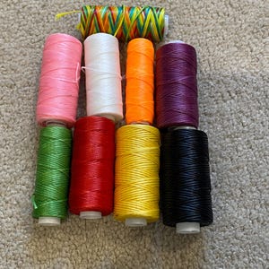May include: Assortment of 10 spools of waxed thread in various colours, including pink, white, orange, purple, green, red, yellow, and black.