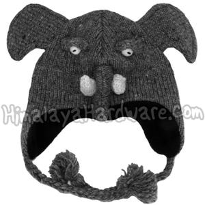 Könnte beinhalten: Graue gestrickte Elefantenmütze mit weißen Filzdetails und schwarzen Fleece-Ohrenklappen. Die Mütze hat zwei graue Bommel, die an den Ohrenklappen befestigt sind.