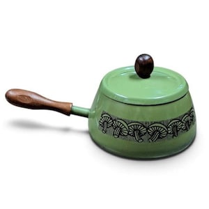 May include: A light green enameled metal saucepan with a matching lid. The pot features a dark brown wooden handle and a dark brown wooden knob on the lid. A black graphic band of repeating mushroom illustrations encircles the base of the pot.