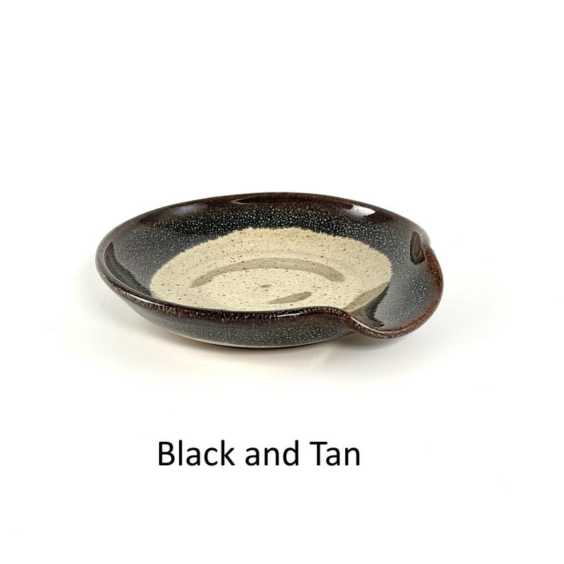 Black and Tan handcrafted spoon rest, shallow round shape with notch for spoon handle, formed on a potter's wheel.