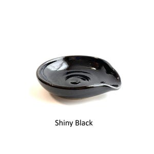 Shiny black glaze, handcrafted spoon rest, shallow round shape with notch for spoon handle, formed on a potter's wheel.
