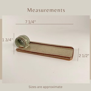 May include: A ceramic incense holder with a light green cylindrical incense holder and a rectangular tray. The tray is approximately 18.4 cm long and 6.4 cm wide. The incense holder is 4.4 cm tall. The text "Measurements" is visible.
