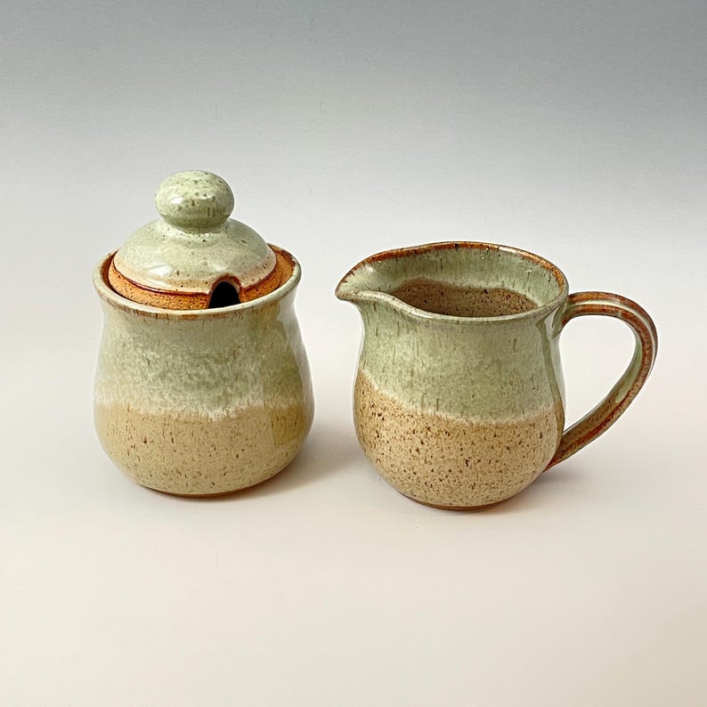 Peut inclure: Un ensemble sucrier et cr&eacute;mier en c&eacute;ramique avec un gla&ccedil;age vert et beige. Le pot &agrave; cr&egrave;me a une poign&eacute;e et le sucrier a un couvercle.