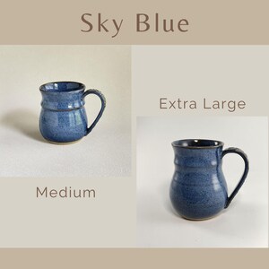 May include: Two sky blue ceramic mugs with a speckled finish and a rounded body shape. One mug is labeled Medium and the other is labeled Extra Large. Both mugs feature a curved handle and a flared rim, showcasing a consistent blue glaze.