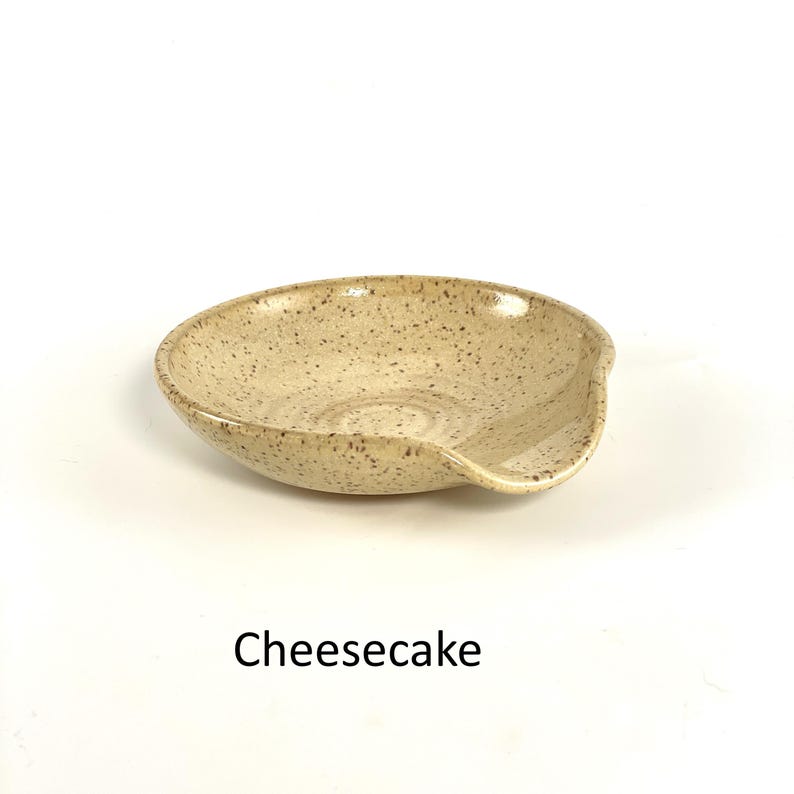 Cheesecake glazed handcrafted spoon rest, shallow round shape with notch for spoon handle, formed on a potter's wheel.